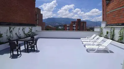 a patio with chairs and tables on a roof at IVY Laureles Apartamentos in Medellín