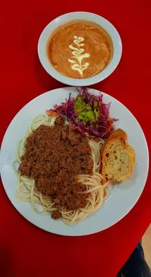 a plate of spaghetti and a cup of coffee on a red table at Hotel Colonial Manizales in Manizales