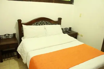 a bedroom with a bed with an orange and white blanket at Hotel Colonial Manizales in Manizales