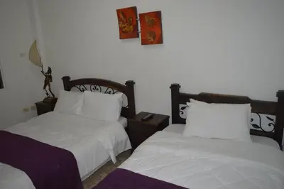 two beds in a room with white sheets and pillows at Hotel Colonial Manizales in Manizales