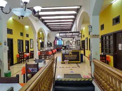a hallway of a building with tables and chairs at Hotel Colonial Manizales in Manizales