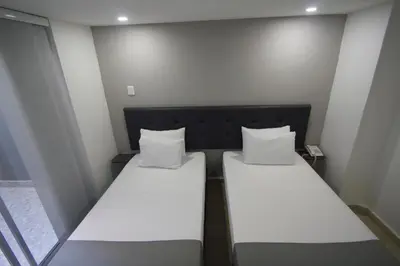 two beds in a small room with white pillows at Element Hotel in Medellín