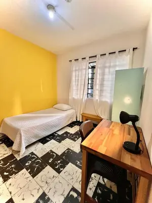 a bedroom with a bed and a table and a window at Selvática Alojamiento Eco in Medellín