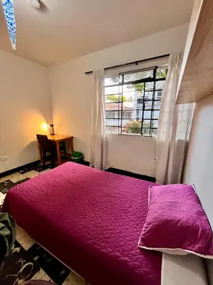 a bedroom with a purple bed and a window at Selvática Alojamiento Eco in Medellín