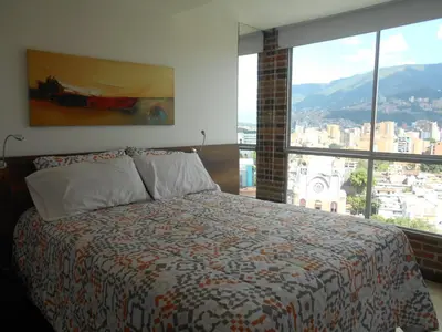 a bedroom with a bed and a large window at Apartasuites AV in Medellín