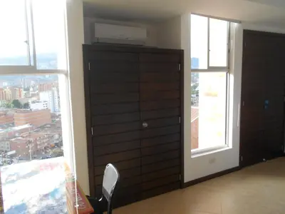 a bedroom with a dresser and a large window at Apartasuites AV in Medellín