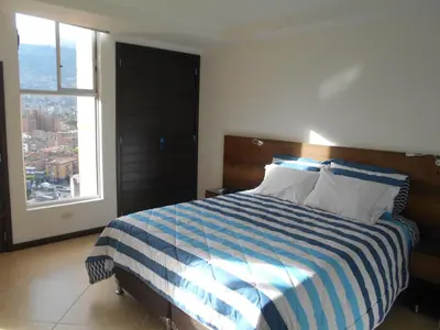 a bedroom with a blue and white bed with a window at Apartasuites AV in Medellín