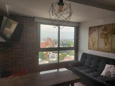 a living room with a couch and a large window at Apartasuites AV in Medellín