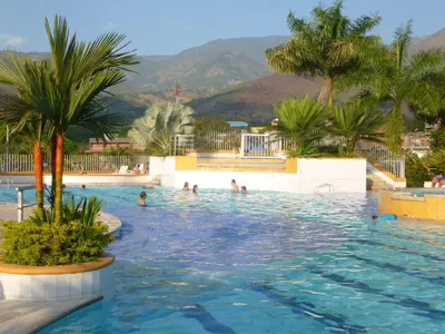 a swimming pool with palm trees and people in it at San Jeronimo Cabaña in San Jerónimo