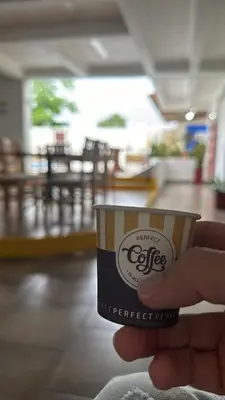 a hand holding a cup of coffee in a restaurant at Monteverde Hotel in La Dorada