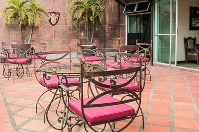 a group of tables and chairs with pink cushions at Hotel Plaza Garibaldi in Caldas
