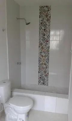 a bathroom with a toilet and a mosaic tile wall at Cabaña Familiar La Aldea Doradal in Gesen