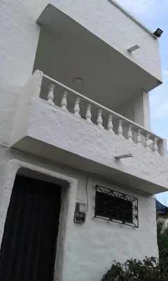 a white building with a balcony and a door at Cabaña Familiar La Aldea Doradal in Gesen