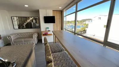 a living room with a large wooden table and a large window at Aptos vista al Embalse, frente al lago, Restaurantes, Bares in Guatapé
