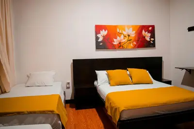 two beds in a room with a painting on the wall at Casabella Hotel in Manizales
