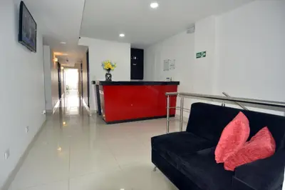 a living room with a black couch with red pillows at Hotel Granada Plaza in Manizales