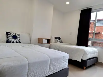 a bedroom with two beds and a window at Hotel Granada Plaza in Manizales