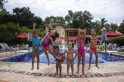 a group of children in bathing suits standing in front of a swimming pool at Hosteria Tonusco Campestre in Santa Fe de Antioquia