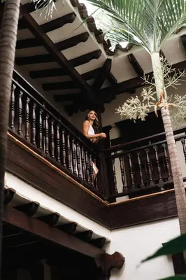 a woman sitting on the balcony of a building at Nueva Granada Hotel Colonial -Centro Histórico- in Santa Fe de Antioquia