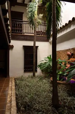 two palm trees in front of a building with a balcony at Nueva Granada Hotel Colonial -Centro Histórico- in Santa Fe de Antioquia