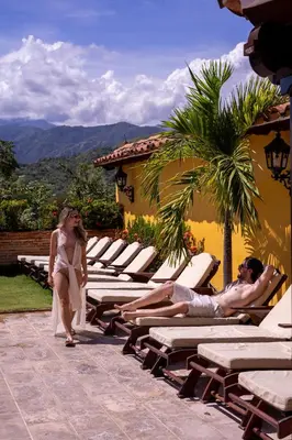 a woman walking next to a row of lounge chairs at Nueva Granada Hotel Colonial -Centro Histórico- in Santa Fe de Antioquia