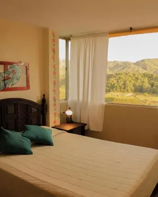 a bedroom with a large bed with a large window at Casa Encuentro Ecolodge, Outdoor Gym and Yoga in Guatapé
