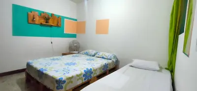 a small bedroom with two beds and a fan at Hostal Paz y Vida in Medellín