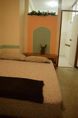 a bedroom with two beds and a door with a plant at Hostal Paz y Vida in Medellín