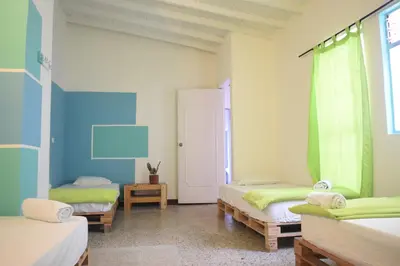 a room with three beds and a window at Hostal Paz y Vida in Medellín