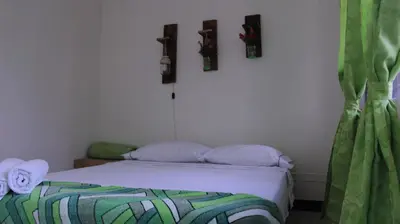 a bedroom with a bed with white sheets and green curtains at Hostal Paz y Vida in Medellín