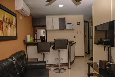 a living room with two chairs and a kitchen at Apartamentos en el Poblado in Medellín