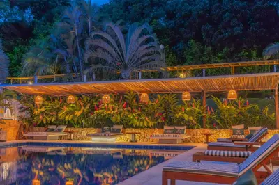 a resort pool with lounge chairs and palm trees at Hotel Villa Camila in La Pintada