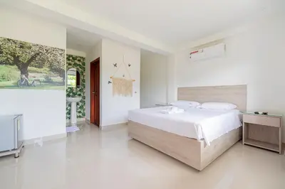 a white bedroom with a bed and a tv at Hotel Villa Camila in La Pintada