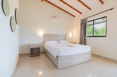 a white bedroom with a bed and a window at Hotel Villa Camila in La Pintada