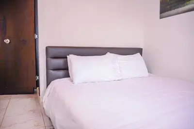 a white bed with a silver headboard and white pillows at Manilla House in Medellín