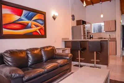a living room with a leather couch and a kitchen at Manilla House in Medellín