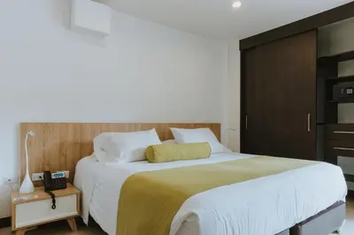a bedroom with a large bed and a telephone at Travelers Rio Verde Living Suites in Rionegro