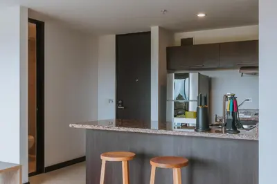 a kitchen with two wooden stools at a counter at Travelers Rio Verde Living Suites in Rionegro
