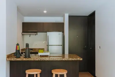 a kitchen with a counter and two stools at Travelers Rio Verde Living Suites in Rionegro