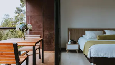 a bedroom with a bed and a table with a vase of flowers at Travelers Rio Verde Living Suites in Rionegro