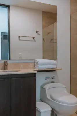 a bathroom with a toilet and a sink and a mirror at Travelers Rio Verde Living Suites in Rionegro