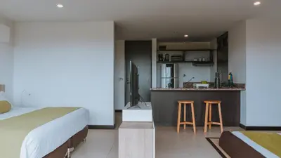a bedroom with a bed and a kitchen with a bar at Travelers Rio Verde Living Suites in Rionegro