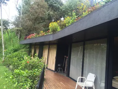 a deck with two chairs and flowers on a house at Cabañas el Retorno in Guatapé