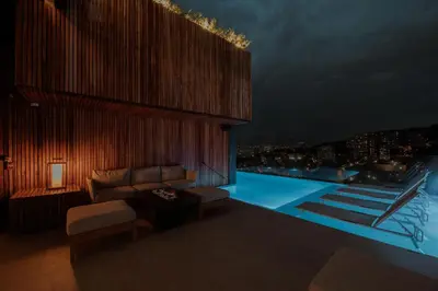 a living room with a couch and a pool at night at Binn Hotel in Medellín