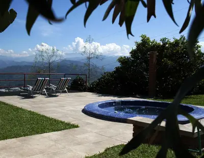 a patio with chairs and a hot tub with a view at Finca Hotel Villa Clara in Chinchiná