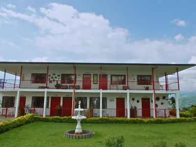 a large white building with red doors and a fountain at Finca Hotel Villa Clara in Chinchiná