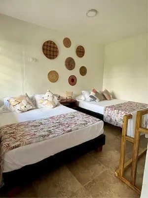 two beds in a room with twoitures on the wall at Finca Hotel Villa Clara in Chinchiná