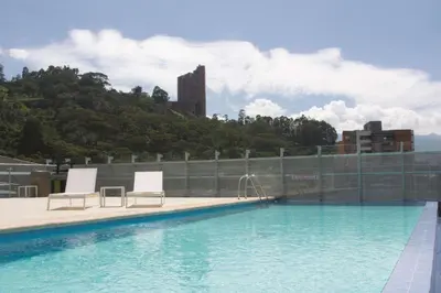 a swimming pool with two chairs and a water slide at La Quinta by Wyndham Medellin in Medellín