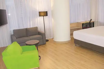 a bedroom with a bed and a couch and a chair at La Quinta by Wyndham Medellin in Medellín