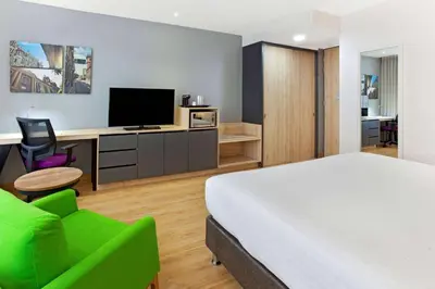 a bedroom with a bed and a desk with a television at La Quinta by Wyndham Medellin in Medellín